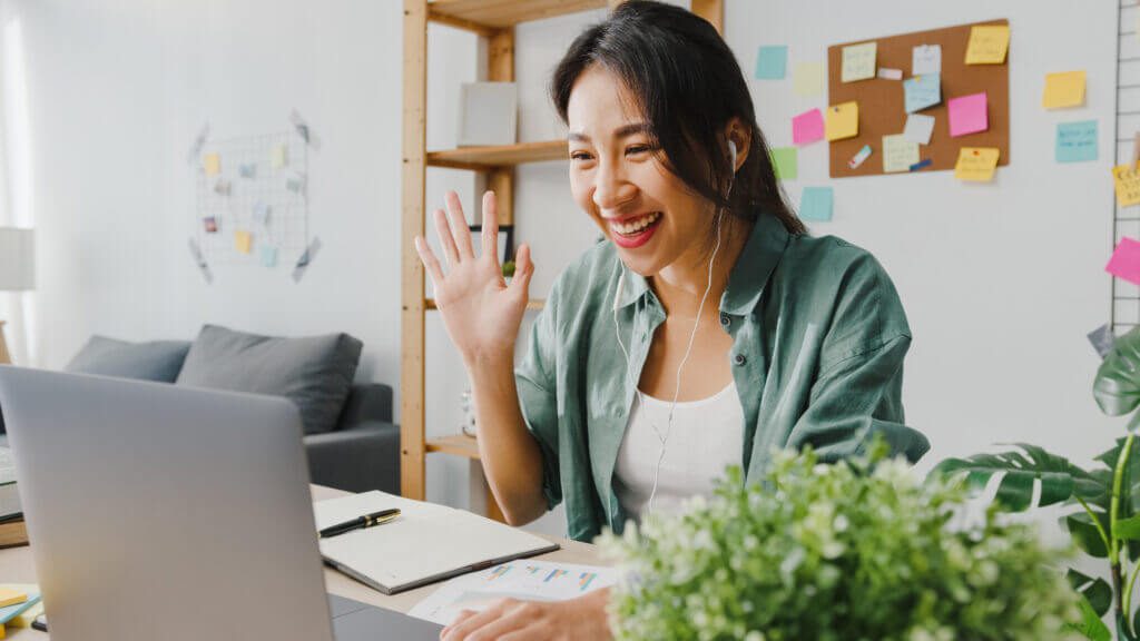 Asian woman using laptop talk to colleagues about plan in video call while smart working from home at living room.